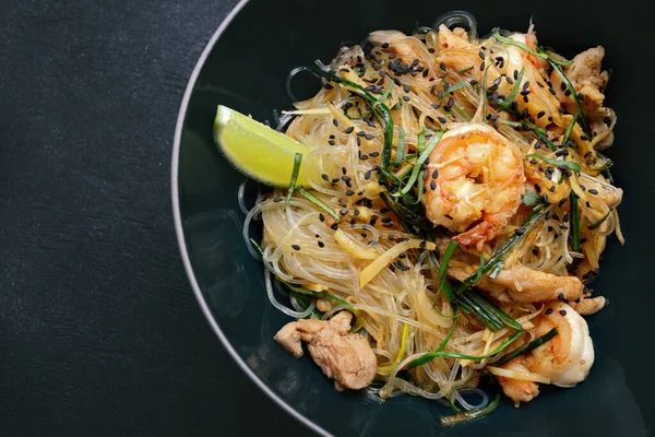 Rice vermicelli with shrimp, meat and spices, on gray concrete
