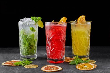 Siyah arka planda, gri betonda 3 farklı limonata.