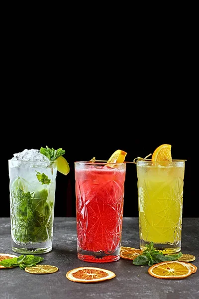 3 Different lemonades on a black background, on gray concrete