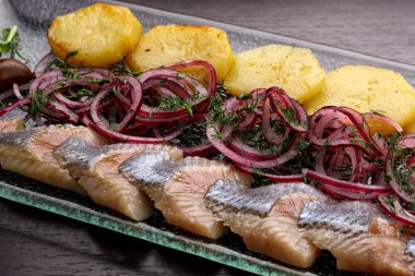 Patates, soğan ve zeytinli dilimlenmiş ringa fileto.