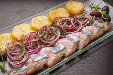Patates, soğan ve zeytinli dilimlenmiş ringa fileto.
