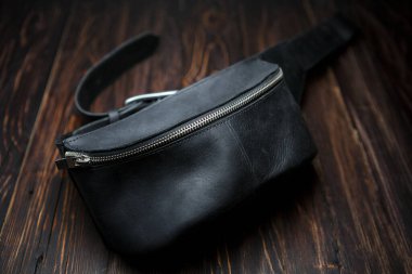 Kemerli siyah deri çanta, ön manzara, ahşap arka plan. Alçak alan derinliği