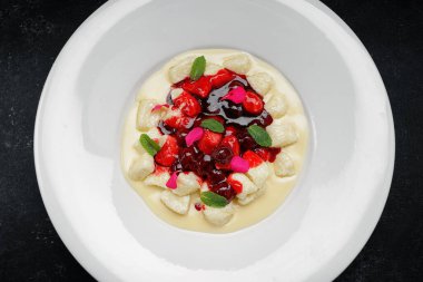 Beyaz bir tabakta kirazlı, ekşi kremalı, tembel börekler.