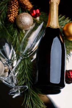 Bir Noel ağacının dallarında bir şişe şarap, gözlük ve koni ile, sığ bir tarla derinliğinde.