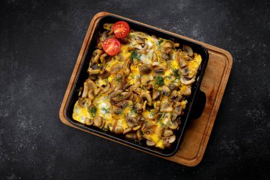 Mantarlı omlet, soğan ve dereotlu, tavada, gri betonda.