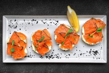 Tabakta füme somonlu sandviç, gri beton.