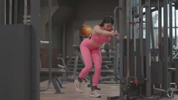 젊은 여자가 넓적다리와 다리 근육을 훈련시키기 위해 다리를 드는 크로스오버를 하고 있다. 엉덩이 훈련. 전문 여성 운동 선수는 다리 운동을 한다 — 비디오