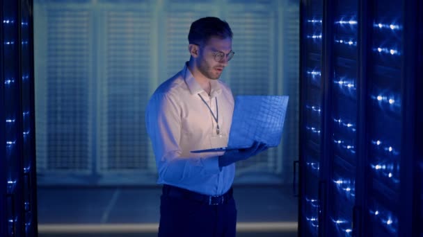 Male Server Engineer in Data Center. IT engineer inspecting a secure server cabinet using modern technology laptop coworking in data center. — Stock Video