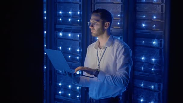 Инженер-мужчина в центре обработки данных. ИТ-инженер, осматривающий защищенный серверный шкаф с использованием современных технологий. — стоковое видео