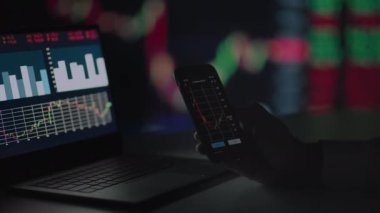 Yatırımcı cep telefonundaki borsa verilerini kontrol ediyor. Akıllı telefondaki borsayı analiz eden bir adam.