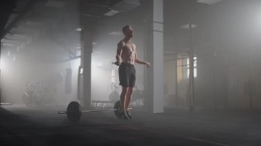Genç adam spor salonunda ip atlama egzersizi yapıyor. Sporcu adam spor salonunda sıkı çalışıyor..