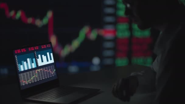 Um profissional com óculos olha para a tela do monitor do computador e pensa em analisar o mercado de valores mobiliários. Brooding intrigante corretor espera o crescimento das ações — Vídeo de Stock