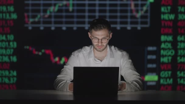 Młody biały człowiek handlowiec pracujący w laptopie monitorującym i przeglądający online w biurze handlowym. Mężczyzna broker następujące stawki i zakłady. Menedżer SMS-ów na ekranie. — Wideo stockowe