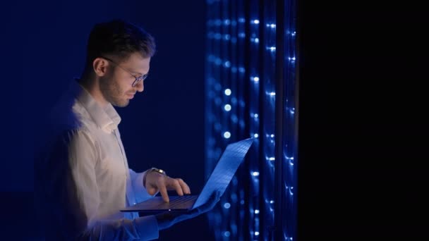 IT-Spezialisten des Rechenzentrums arbeiten im sicheren Serverraum des Cyberspace. Männlicher Administrator zeigt auf Fehlerserver-Schrank, der Diagnose auf Laptop-Computer ausführt — Stockvideo