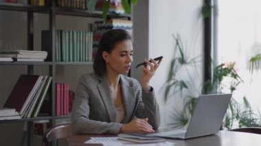 Akıllı telefon cihazı tutan, ses tanıma sistemi kullanan, sesli mesaj kaydeden ya da cep telefonu asistanıyla konuşan bir kadın. Kimlik doğrulama, iletişim, çevrimiçi teknoloji kavramı.