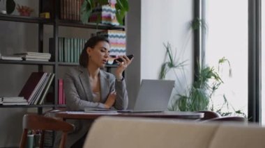 Akıllı telefon cihazı tutan, ses tanıma sistemi kullanan, sesli mesaj kaydeden ya da cep telefonu asistanıyla konuşan bir kadın. Kimlik doğrulama, iletişim, çevrimiçi teknoloji kavramı.