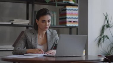 İş kadını defterine bir şeyler yazıyor. Girişimci bir kadın öğrenci, iş yerindeki bilgisayarın yanında not yazmayı öğreniyor. Bir kadın eli masanın üzerine beyaz boş bir defter yazıyor..