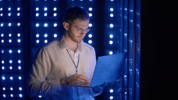 Προσωπογραφία του ανθρώπου που εργάζεται σε αίθουσα διακομιστή με φορητό υπολογιστή. τεχνικός κάνει τσεκ-απ στο δωμάτιο του σέρβερ. Καυκάσιος μηχανικός με γκρι σακάκι εργάτη — Αρχείο Βίντεο