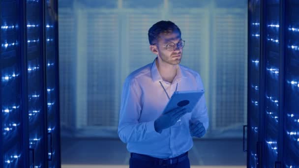 Technicien informatique dans la salle de serveur numérique de centre de données contrôlant le travail des armoires de serveur rack avec une tablette. Ingénieur serveur professionnel au travail. — Video