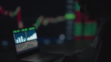 Finansal Analizci, Multi-Monitor Workstation ve Real-time Borsa ve Borsa Çizelgeleri ile bir bilgisayar üzerinde çalışıyor. İşadamı Yatırım Bankası Şehir Merkezi Ofisinde Gece Çalışıyor.