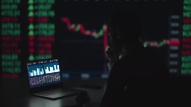 Finansal Analizci, Multi-Monitor Workstation ve Real-time Borsa ve Borsa Çizelgeleri ile bir bilgisayar üzerinde çalışıyor. İşadamı Yatırım Bankası Şehir Merkezi Ofisinde Gece Çalışıyor.