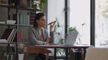 Tarz sahibi genç bir kadın internette sörf yaparak modern kafedeki bir masada oturuyor ve gülümsüyor. Ofisteki genç iş kadını cep telefonu kullanıyor.