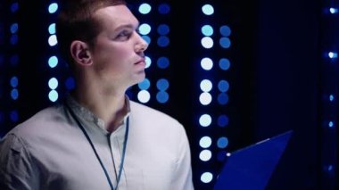 Bilgi Dijitalleştirme Konsepti: Bilgi Teknolojisi Uzmanı Sunucu Rafları 'nın önünde dizüstü bilgisayarla duruyor, Veri Merkezi' ni dokunmatik bir hareketle etkinleştiriyor. Ağ Verisi