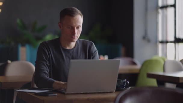 Przystojny biznesmen w okularach pilnie pracujący na laptopie w kawiarni. Mężczyzna pisze na klawiaturze i szuka nowej pracy w internecie w kawiarni. Koncepcja przedsiębiorstwa — Wideo stockowe