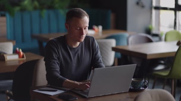 Przystojny biznesmen w okularach pilnie pracujący na laptopie w kawiarni. Mężczyzna pisze na klawiaturze i szuka nowej pracy w internecie w kawiarni. Koncepcja przedsiębiorstwa — Wideo stockowe