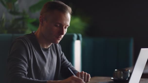 Egy komoly ember egy üzleti tanuló, aki egy asztalnál tanul és üzenetet ír egy laptopon. Szöveg beírása a billentyűzeten — Stock videók