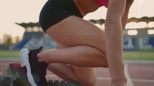 Egy fiatal női sportoló elmélázik, és felkészül egy sprintverseny kezdetére egy napsütéses napon a stadion futópadján. — Stock videók