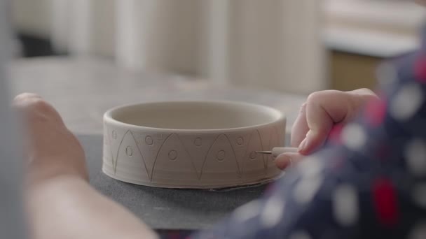 Vrouw handen tijdens het schilderen op keramische platen. Pottenbakker workshop van het maken van handgemaakte klei gerechten. Kunstenaar creëert een prachtig patroon op aardewerk in een aardewerkplaats. Close-up, slow motion — Stockvideo