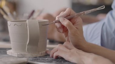 Kadın elleri seramik tabaklar üzerinde resim yaparken. Potter el işi kil tabakları atölyesi. Sanatçı çömlekçilik atölyesinde güzel bir kalıp yaratıyor. Yakın çekim, yavaş çekim