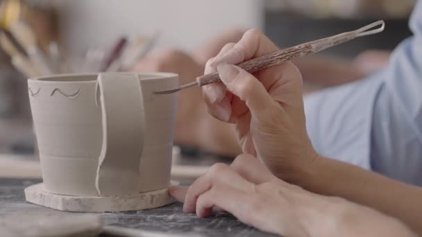 여자들은 세라믹 판 위에 그림을 그리면서 손을 잡는다. 수공예 질그릇을 만드는 포터 워크 샵. 미술가들은 도자기 작업장에서 질그릇 위에 아름다운 무늬를 그려 넣습니다. 클로즈업, 느린 동작 — 비디오