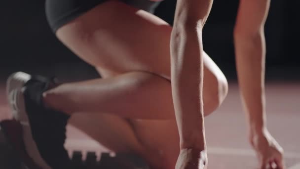 Повільний рух жінка бігунка на старті крупним планом в темряві на стадіоні професійний бігун спортсмен — стокове відео