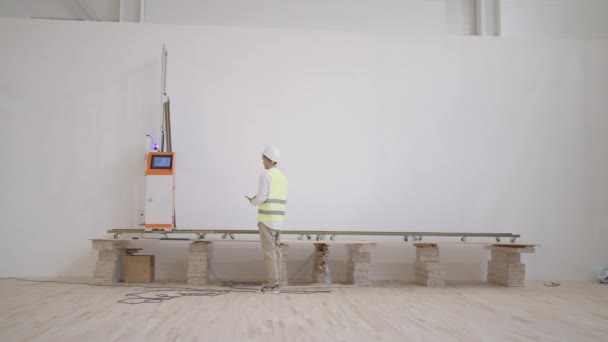 Voorwaarts gerichte mannelijke ingenieur bewaakt de werking van de drukmachine. printerafdrukken op muren — Stockvideo