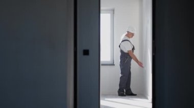 Miğferli bir elektrikçi LED şeritleri takıp kontrol ediyor. Aç ve ışığı ve dekoratif ışıkları kontrol et. Arkaplan ışığının çalışmasına bak.