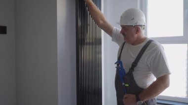Bir tesisatçı bataryaları ve ısıtma sistemini kontrol ediyor. Isıtma sezonu
