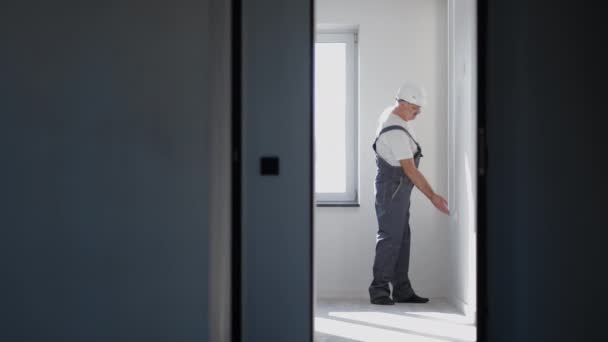 Een elektricien in een helm installeert en controleert LED strips voor verlichting in het appartement. Doe aan en controleer het licht en de decoratieve lichten. Kijk naar de werking van de achtergrondverlichting — Stockvideo