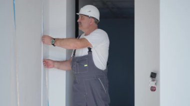 Miğferli bir elektrikçi LED şeritleri takıp kontrol ediyor. Işığı ve ışıklandırmayı kontrol et.