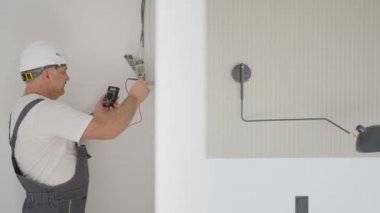 Erkek bir elektrikçi akıllı bir ev sistemine aydınlatma için trafolar yerleştiriyor. Yükleme ışıklandırması