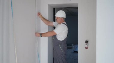 Miğferli bir elektrikçi LED şeritleri takıp kontrol ediyor. Aç ve ışığı ve dekoratif ışıkları kontrol et.