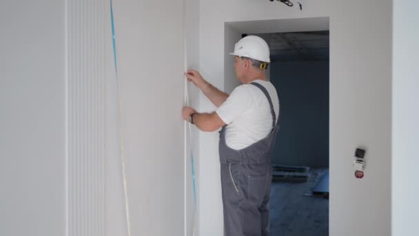 Un electricista masculino instala una tira del led para iluminar las paredes en el sistema casero elegante. Verificación de la instalación Iluminación — Vídeos de Stock