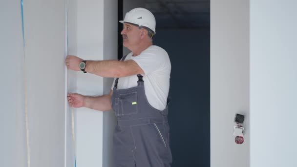 Een elektricien in een helm installeert en controleert LED strips voor verlichting in het appartement. Controleer het licht en de verlichting decoratieve — Stockvideo