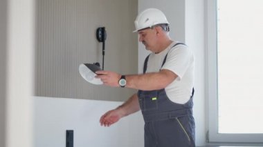 Elektrikçi, tesisat ve onarımdan sonra evdeki lamba lambasının çalışmasını kontrol ediyor.