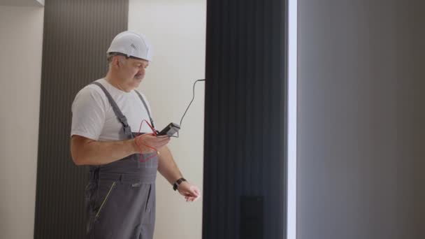 El electricista comprueba el funcionamiento de la unidad de control de pared de las lámparas con el sistema de una casa moderna después de la instalación y enciende la luz de fondo — Vídeos de Stock