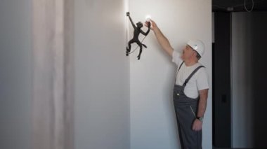 Elektrikçi bir ampul yerleştirir ve çocuk odası için lambanın işleyişini kontrol eder..