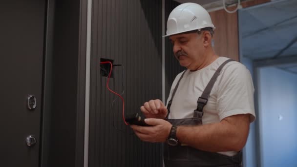 Portrait Electrician checks the operation of the wall control unit of lamps with the system of modern house after installation and repair — Stock Video