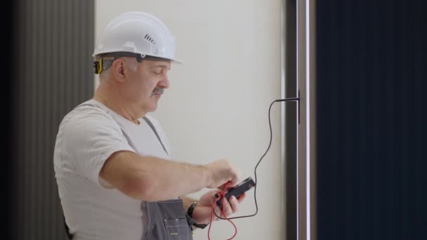 Älterer Elektriker überprüft nach der Installation und Reparatur den Betrieb der Lampenwandsteuerung mit dem System eines modernen Hauses — Stockvideo