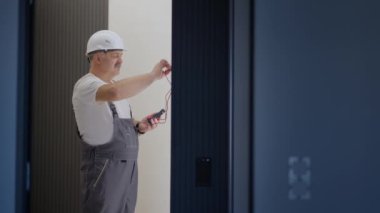 Elektrikçi adam apartmandaki akıllı ev sistemini kurar ve kontrol eder